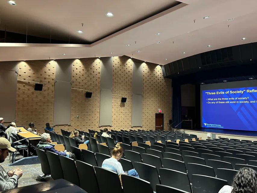 An image of the WVU Gluck theatre with a presentation on MLK in the background. 