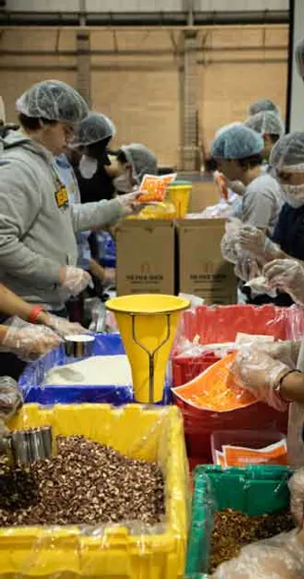 A picture of one of the "packing lines" with volunteers on both sides of the table packing meals.