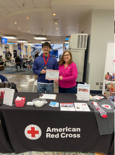 Student and Community Partner from the American Red Cross smile as they hold a certificate presented to the student